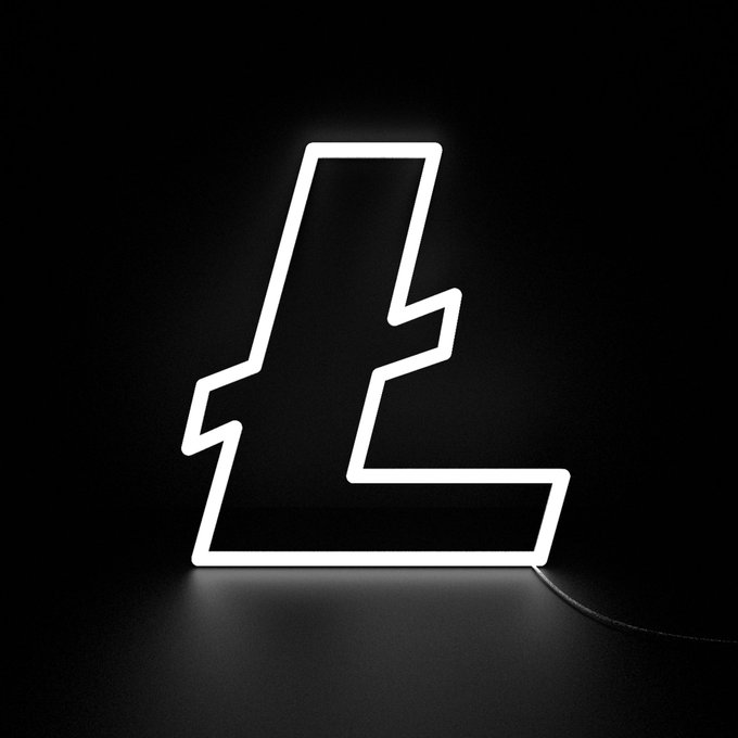 A glowing white neon sign shaped like the letter "L" with jagged, lightning-like edges illuminates a dark room, with a power cord trailing from its base.