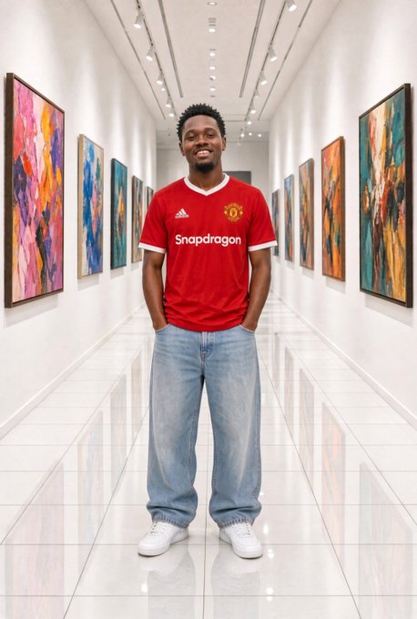 A man wearing a red Manchester United jersey with the Snapdragon sponsor logo stands smiling in a modern art gallery hallway.
