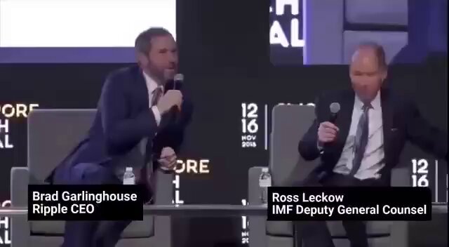 The image shows two men sitting behind a table with microphones, appearing to be engaged in a discussion or presentation. One man has his arms crossed over his chest while the other man holds a microphone, suggesting they are participating in an event where they are addressing an audience. The background features a large screen displaying text related to the IMF and Ripple Ledger ecosystem, indicating that this could be part of a panel discussion on financial topics or a similar event.

The image also contains some text about the Ripple Ledger ecosystem expanding into a multi-trillion dollar market with real tokens emerging as one of the leading utility. This information might suggest that the men are discussing the potential impact and implications of this new financial technology, such as its benefits and risks for investors or the broader economy.