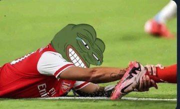A soccer player in a red Arsenal jersey sliding on the grass, with the iconic Pepe the Frog meme face photoshopped over the player's head.