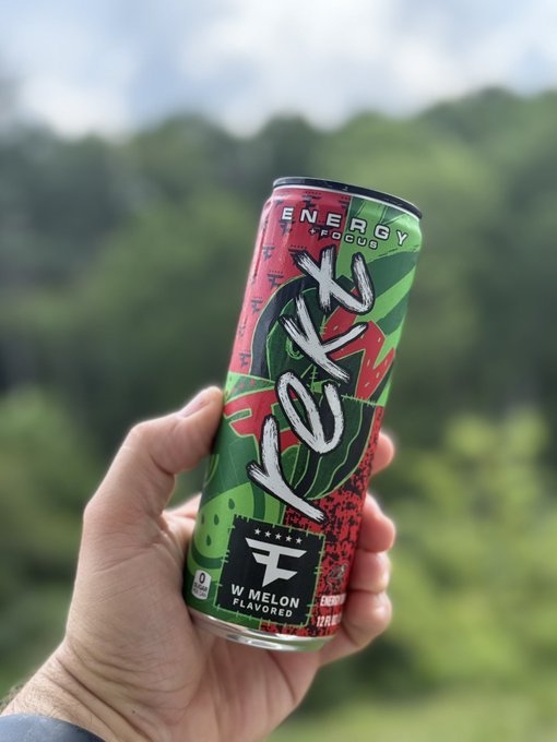 A hand holds a can of REKT W Melon flavored energy drink with a FaZe Clan logo, featuring "ENERGY + FOCUS" and "12 FL OZ" text. This drink is being praised as one of the best functional offerings.