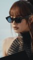 A woman wearing sunglasses and a striped top posing in what appears to be a glamorous setting.