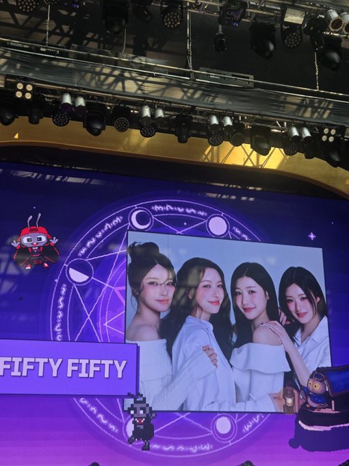 A stage screen displays a photo of four female K-pop idols with the text 'FIFTY FIFTY' partially visible, illuminated by stage lighting.