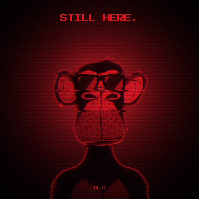 A dark red promotional poster with pixelated text 'STILL HERE.' at the top, featuring a stylized monkey face with round ears and the date '10.17' below.