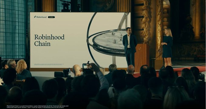 A presenter on stage at an event announces "Robinhood Chain," displayed on a large screen with the Robinhood logo, as the company unveils its own Layer 2 blockchain aimed at bringing stocks and real-world assets onchain.