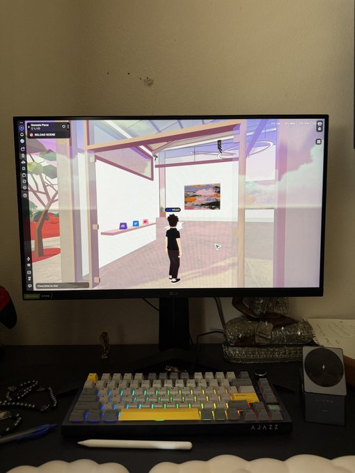 A computer monitor displays a virtual world scene with an avatar standing in a modern, glass-walled room, sitting on a desk above an Ajazz mechanical keyboard and stylus.
