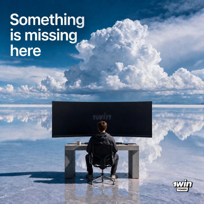 A man sits alone at a desk facing a blank monitor displaying "1win" against a surreal mirrored sky-salt flat landscape, with the tagline "Something is missing here" — reinforcing the post's teaser inviting viewers to guess what's absent from the empty screen, hinting at a 1win Token game.