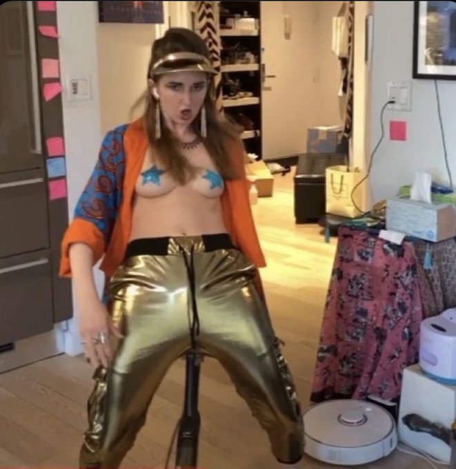 A woman in gold pants and a star-covered top poses for a photo while a robotic vacuum cleaner is visible in the background. The image likely depicts the woman being referenced in the post as a symbol of the perceived recklessness and audacity of the individual who allegedly mishandled $5 billion.