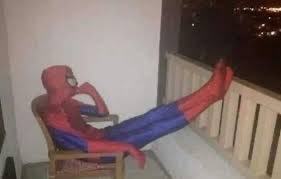 A person in a Spider-Man costume is lounging in a chair on a balcony with their feet propped up on the railing, holding food. The playful image humorously reinforces the post's "engagement hack" theme, using a superhero to suggest that even a casual lunch could be made notable enough to merit an airdrop on X.
