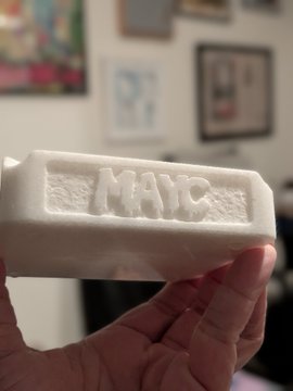 A hand holds up a white styrofoam packaging piece with the word "MATE" embossed on it.