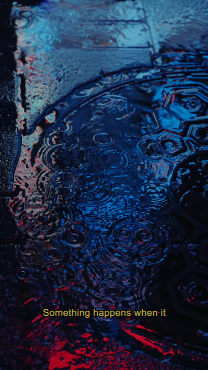 The image features a close-up view of raindrops on a surface, creating an abstract pattern with blue and red colors. The text "Something happens when it" is written below the image, which could be interpreted as a metaphor for the artist's creative process or the idea that art emerges from unexpected sources or moments in life.