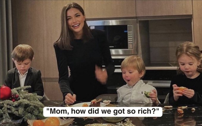 A smiling woman stands in a kitchen with three children around her, with text overlay reading: 'Mom, how did we get so rich?'