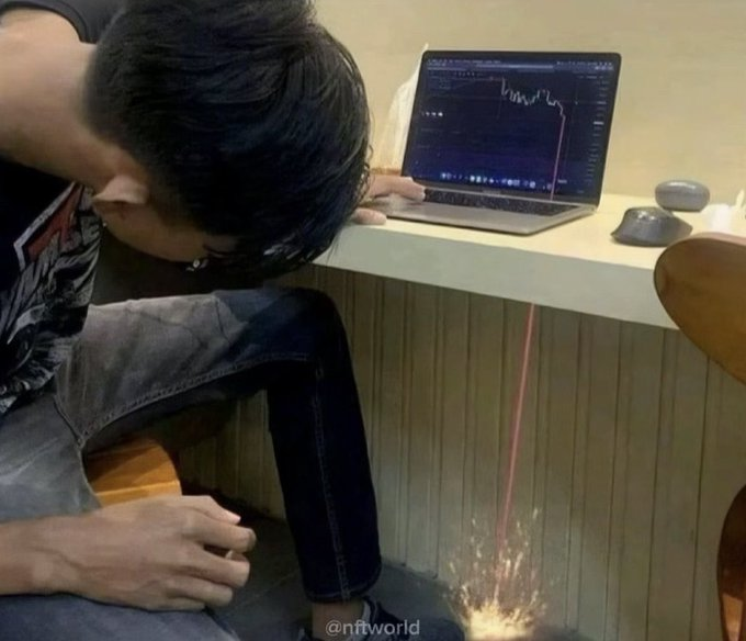 A person sits hunched over a laptop displaying a sharply declining crypto chart, with a red laser-like beam shooting down from the screen to explode on the floor, visually depicting the devastating financial loss after buying a KOL-promoted coin. The watermark "@nftworld" appears in the bottom right corner, tying the meme to the crypto/NFT community's familiar experience of watching influencer-shilled tokens crash.