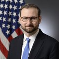 The image shows a man with glasses, a beard, and a blue tie, standing in front of an American flag, presumably Patrick Witt. The post refers to him making a Bitcoin 2026 conference promise about an impending "big announcement" regarding the Strategic Bitcoin Reserve (SBR) that never materialized, noting he has since left his White House position.