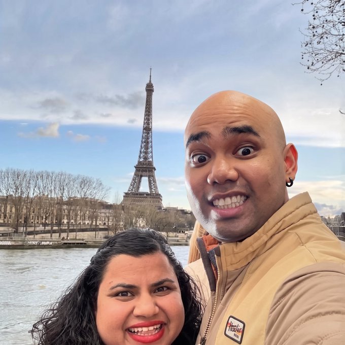 A couple takes a selfie with the Eiffel Tower in the background, smiling as they celebrate their Paris getaway funded by profits from selling $ANSEM at a $350M market cap.