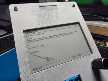 Close-up photo of a portable electronic device, likely an e-ink tablet or notebook, displaying a project outline page in a textured case.