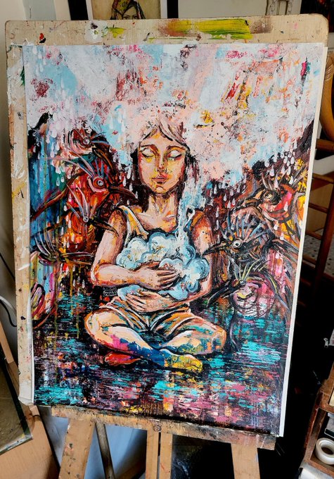 An expressive, colorful acrylic painting on a wooden easel depicting a serene woman with closed eyes holding a cloud, surrounded by mystical creatures like a peacock and dragon, rendered in vibrant blues, oranges, and pinks.