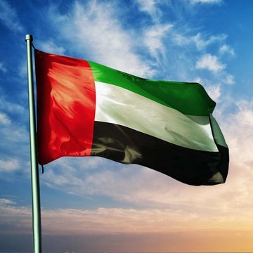 The flag of the United Arab Emirates waves against a cloudy sky, providing visual context for the news about two Binance employees being detained and questioned by UAE authorities. The image symbolizes the location of the reported investigation into potential financial crimes.
