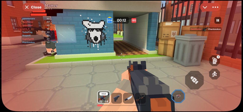 First-person shooter mobile game screenshot showing a pixelated bear graffiti on a blue brick wall, with player scores (204 vs 185), a timer at 00:12, and the player's name 'PhantomAce' displayed.