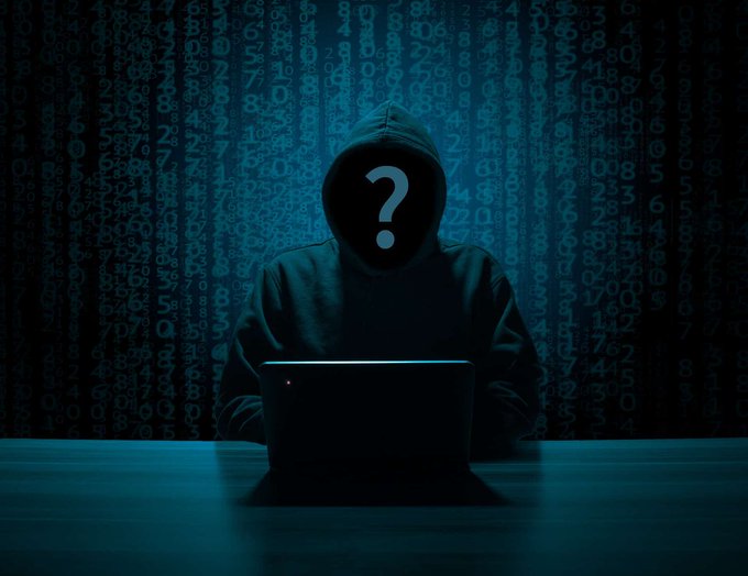 A hooded figure with a question mark on their face sits at a laptop, silhouetted against a background of falling digital numbers in blue tones.