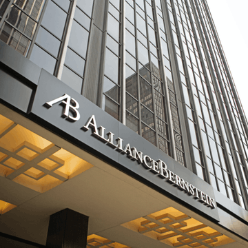 An upward-angled photograph of the exterior of a modern glass office building featuring an "AB AllianceBernstein" sign above its entrance.