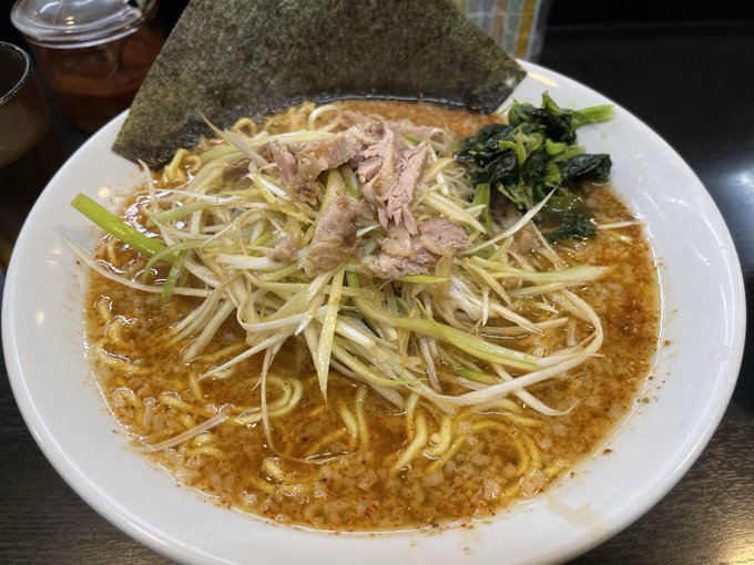 The image features a white plate filled with noodles, meat, and vegetables such as broccoli and greens. The dish appears to be a delicious meal served at a restaurant or home setting. The photo captures the details of the food items, including their colors and arrangement on the plate.