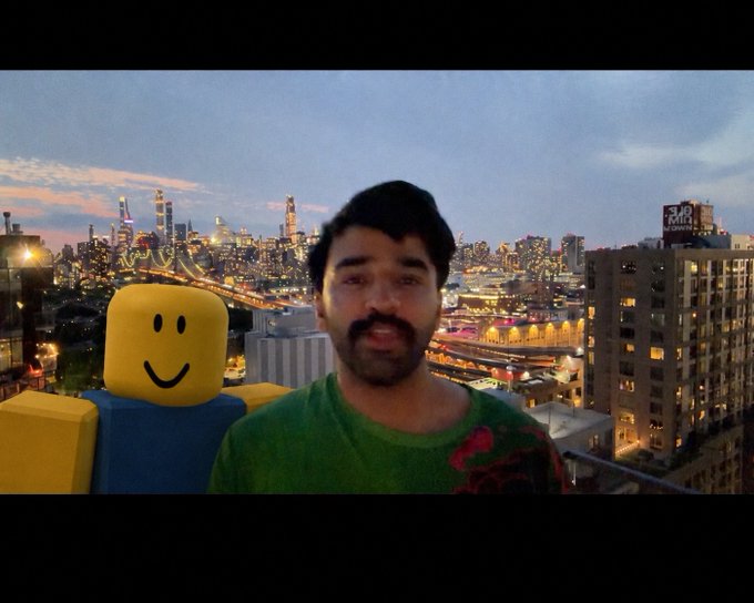 A man on a rooftop overlooking a city skyline poses next to a Roblox "Noob" character figure, with a "The Standard" sign visible in the background. The image appears to be a thumbnail for a video where he discusses and compares AI coding models (GPT 5.6, SOL, TERRA, and LUNA) by testing which one can build the best Roblox game.
