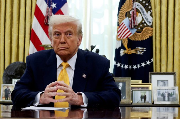 Former President Donald Trump is pictured sitting at a desk in the Oval Office, with American flags and the presidential seal visible in the background. This image likely accompanies a statement about his concerns regarding China's dominance in the crypto market.