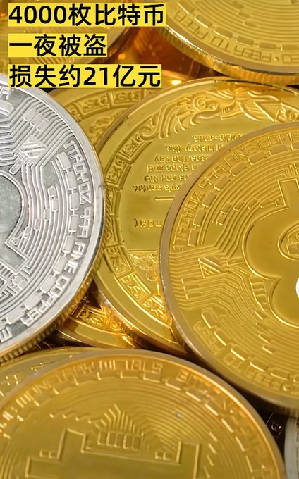 A close-up of physical Bitcoin coins with Chinese text overlay reading '4000枚比特币一夜被盗 损失约21亿元' (4000 Bitcoins stolen overnight, approximately 2.1 billion yuan lost).