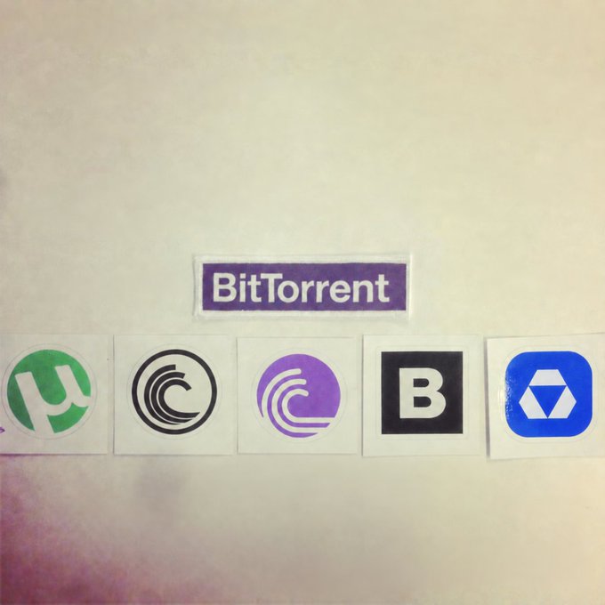 A collection of BitTorrent client stickers, featuring the logos of uTorrent, BitComet, qBittorrent, BitTorrent (B), and Deluge, displayed beneath a purple "BitTorrent" sticker—inviting viewers to choose their favorite BitTorrent client.