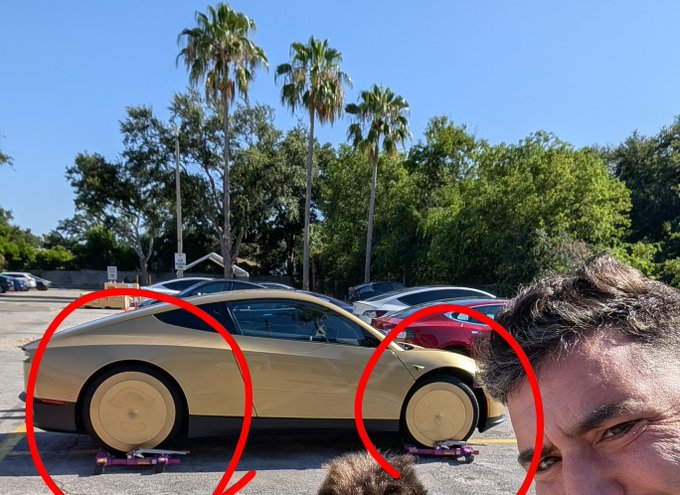 A man poses in the foreground next to a tan Tesla Cybertruck with its distinctive solid wheels circled in red, parked in a lot with palm trees.