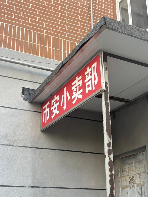 Red Chinese sign reading "巾安小卖部" (Jin An Small Shop) mounted above a weathered storefront entrance.