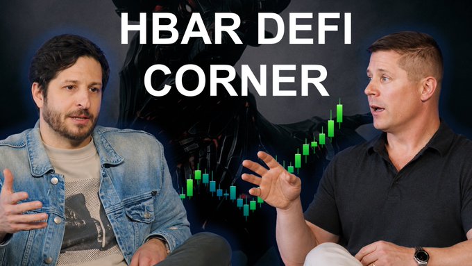 The image shows a man wearing blue jeans sitting on a couch with another man, who appears to be holding a book open in front of him. They seem to be having an interesting discussion or conversation related to the topic of Bitcoin, possibly about its future value. A banner at the top of the image says "Another $HBAR DeFi Corner is live & isn' t one to miss! We disagree on perps & want your feedback." This suggests that there might be a debate or disagreement between the two men regarding their opinions on a particular matter related to Bitcoin.