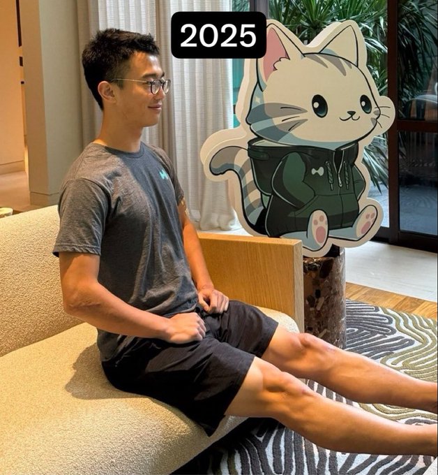 A man sits smiling on a couch beside a cartoon cat cutout wearing a green hoodie, with "2025" displayed at the top. The image reflects the post's message of embracing a new chapter with the Hypurr mascot, symbolizing optimism and fresh goals for the year ahead.