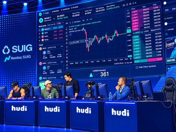 Four traders sit at gaming setups with 'hudi' branded desks in front of massive screens showing the NEAR token at $4.9855 and a current balance of $361, with 'Nasdaq: SUIG' visible.