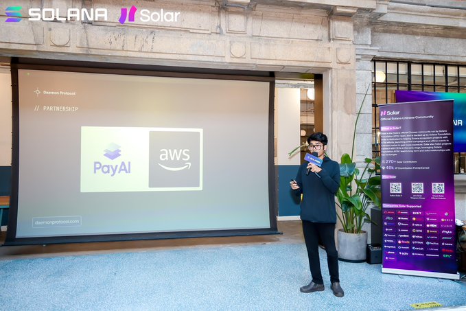 A man speaking into a microphone at an outdoor event with Solana and Solar branding, standing in front of a presentation screen announcing a 'PARTNERSHIP' between PayAI and AWS.