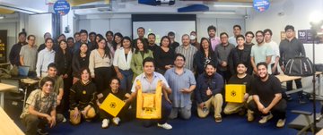 A distorted, mirrored image of a group of people, some wearing yellow uniforms, standing in what appears to be an office or warehouse.