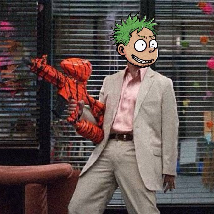 A humorous edited image showing a man in a tan suit holding a Spider-Man action figure, with a cartoonish green-haired face (in the style of the 'Garfield minus Garfield' or 'Evil Mark' meme) superimposed over his head.