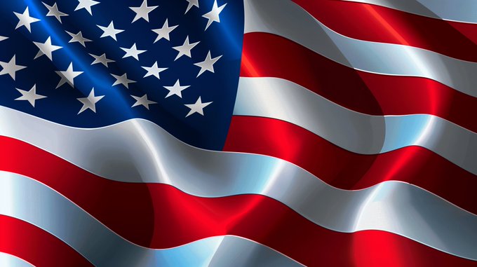 A close-up view of the American flag waving, displaying its red and white stripes and blue field with white stars in a flowing, satin-like texture.