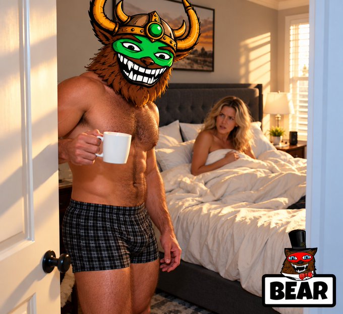 A shirtless man in plaid boxer shorts stands in a bedroom doorway holding a white coffee mug, his face obscured by a horned helmet with a green grinning mask; a woman sits in bed behind him, with a 'BEAR' logo featuring a top-hatted mascot in the corner.