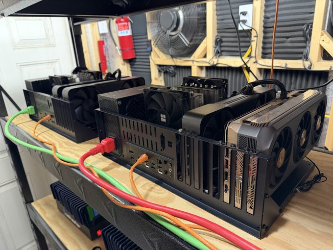 A cryptocurrency mining rig setup with multiple GPUs, cooling fans, and connected power cables sits on a wooden workbench in what appears to be a workshop or garage.