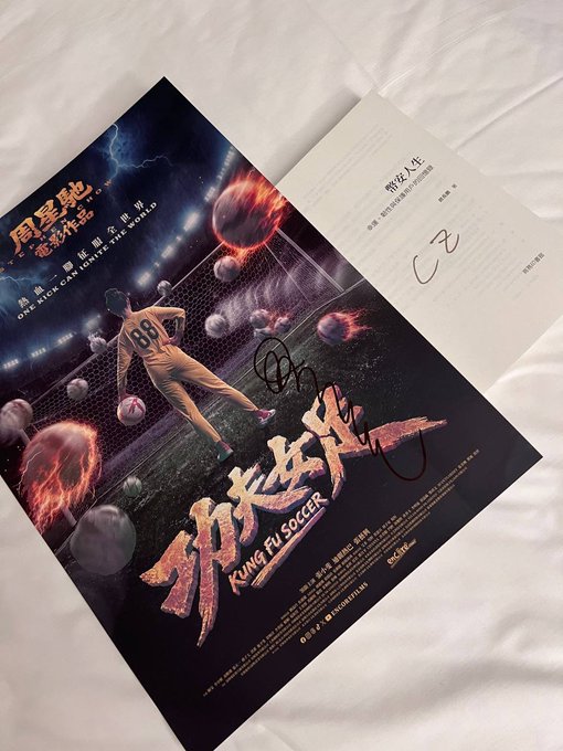 A signed promotional poster for the movie 'Kung Fu Soccer' (功夫足球) featuring a soccer player on a fiery field with planets, alongside a page from a booklet signed in marker.