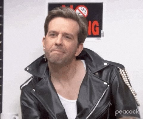 The image features a man wearing a leather jacket with zippers and a white shirt underneath. He has his mouth open as if he's making a funny face or saying something humorous. The background of the image shows a sign that says "No Smoking", indicating that smoking is not allowed in this area.