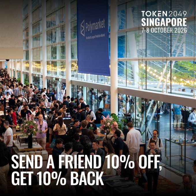 A crowded networking event for TOKEN2049 Singapore (7-8 October 2026), with a Polymarket banner overhead and promotional text reading "SEND A FRIEND 10% OFF, GET 10% BACK." The image visually reinforces the post's referral program message, showing the type of bustling in-person experience attendees can earn discounts toward by sharing their ticket codes.
