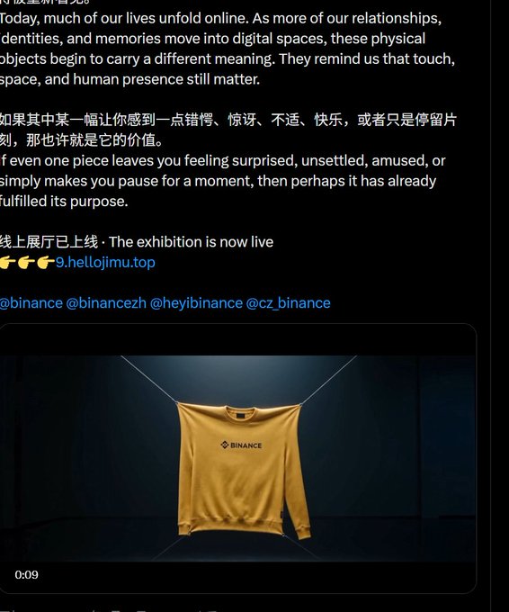 A yellow Binance-branded sweatshirt hangs on a clothesline in a dimly lit dark space, displayed beneath Chinese and English text referencing an online exhibition ("9.hellojimu.top") and tagged @binance, @binancezh, @heyibinance, and @cz_binance, visually tying the physical garment to the post's meme aesthetic about Binance's "matrix number" and dual saint hype.
