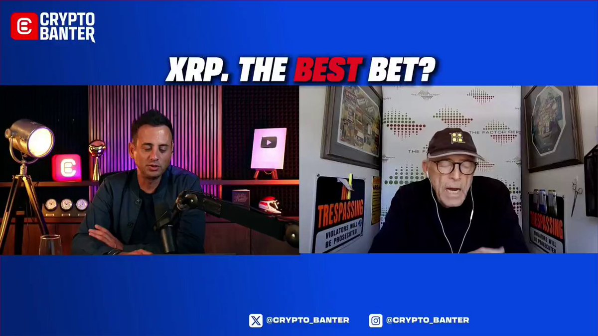 The image features two men sitting at a table, with one man wearing glasses and the other wearing a baseball cap. They are both talking into microphones, suggesting that they might be hosting a podcast or radio show. The background of the image includes a blue banner with white text that reads "XRP. XPT. THE BEST BEAT?", which is likely related to the content being discussed by the hosts.