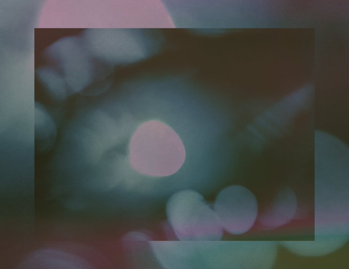 Moody, abstract photograph with a vintage film aesthetic, featuring soft pink and teal bokeh light orbs overlaid on a dark square frame.