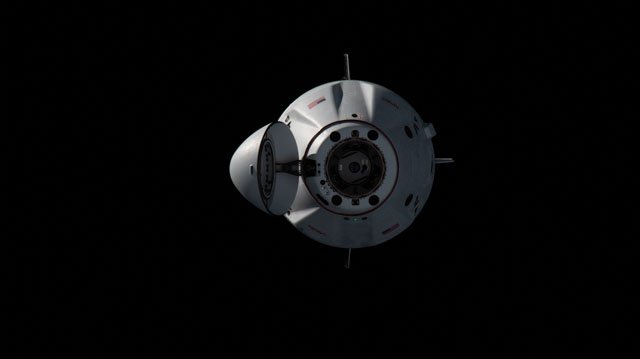 A space capsule or spacecraft floating against a dark black background in what appears to be outer space.