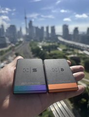 A hand holds two sleek self-custody hardware wallets against the backdrop of the Frankfurt skyline, one displaying the Solana "SOL" logo and the other the Bitcoin "₿" symbol—visually reinforcing the post's message about securing diverse chains through self-custody.