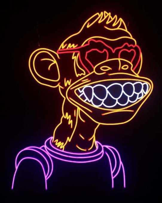 A neon sign depicting a monkey wearing a red cap, displaying its teeth, and a pink/purple shirt against a black background.